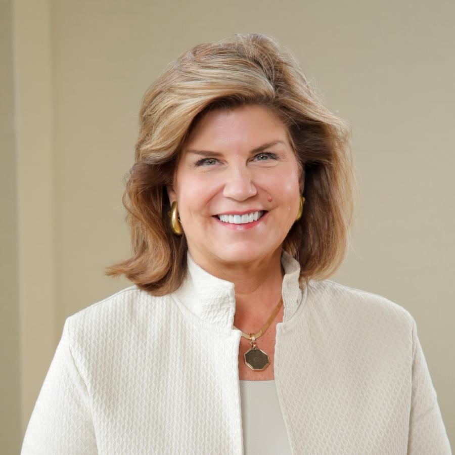 Women with shoulder length hair and a cream suit jacket smiles