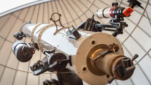 Large white telescope points towards the afternoon sky through an open observatory dome