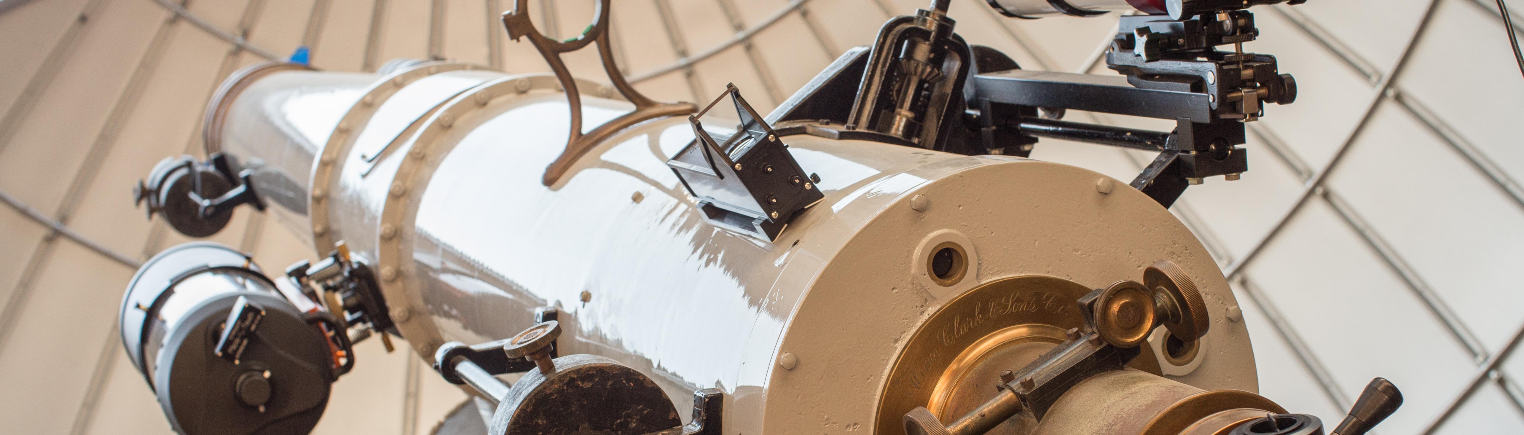 Large white telescope points towards the afternoon sky through an open observatory dome