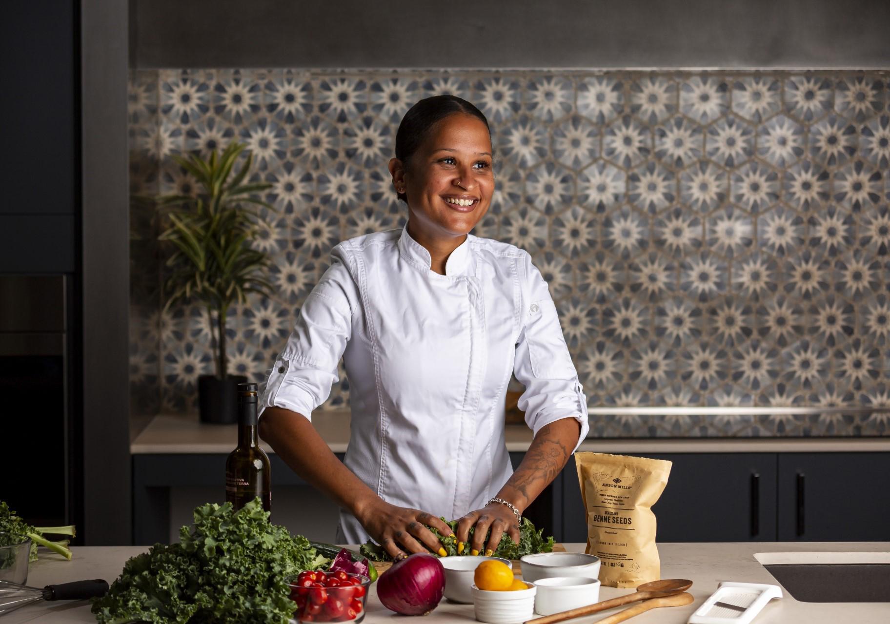 Artwork depicting a portrait of a Black woman with short hair in a purple shirt with a flowering cabbage in the foreground