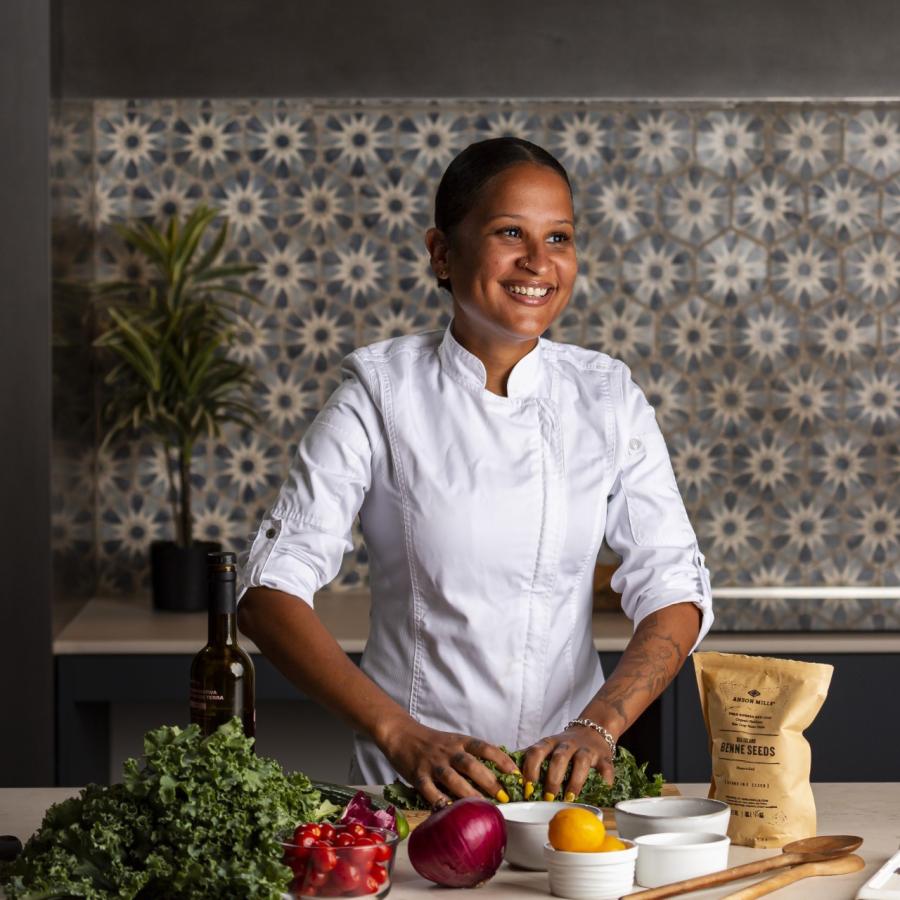 Artwork depicting a portrait of a Black woman with short hair in a purple shirt with a flowering cabbage in the foreground