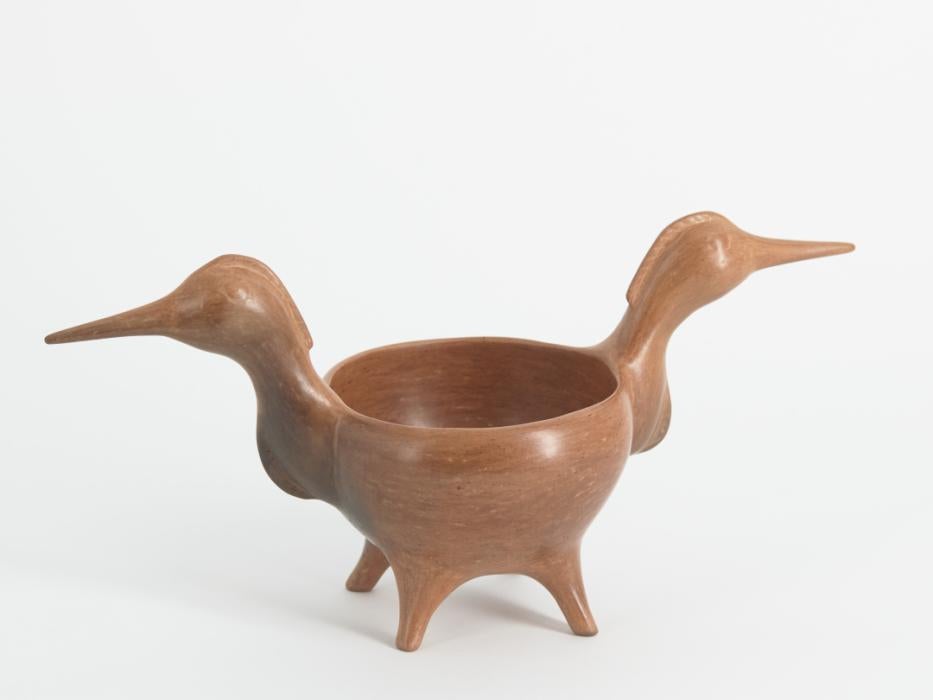 Black and light grey wedding jug with a short basket handle that connects two long necks with elongated narrow spouts. The jug is decorated with incised feather forms on both sides with a single feather on the bowl that splits into two feathers along each spout.