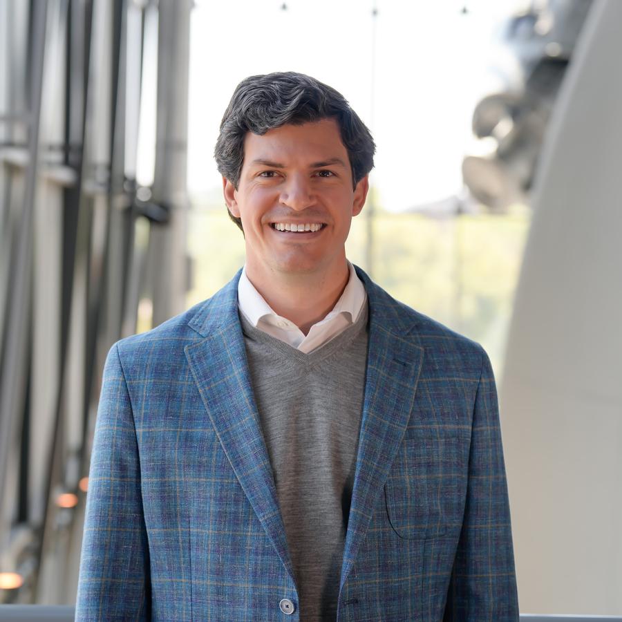 Man in light blue plaid jacket with gray shirt smiles