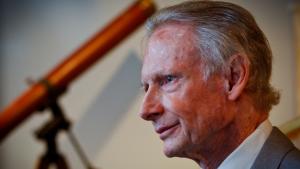Older man in profile with wooden telescope in the background