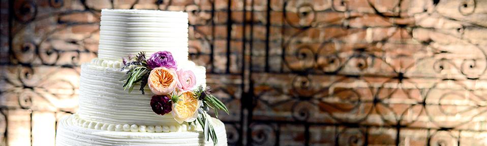 3 Tiered white wedding cake sits in front of the Philip Simmons wrought iron gate at the State Museum.