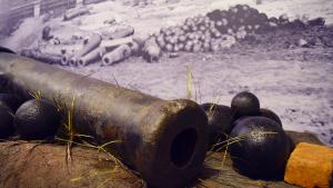 Large antique cannon on exhibition with photo backdrop of a destroyed Main St. in Columbia, SC c. 1865