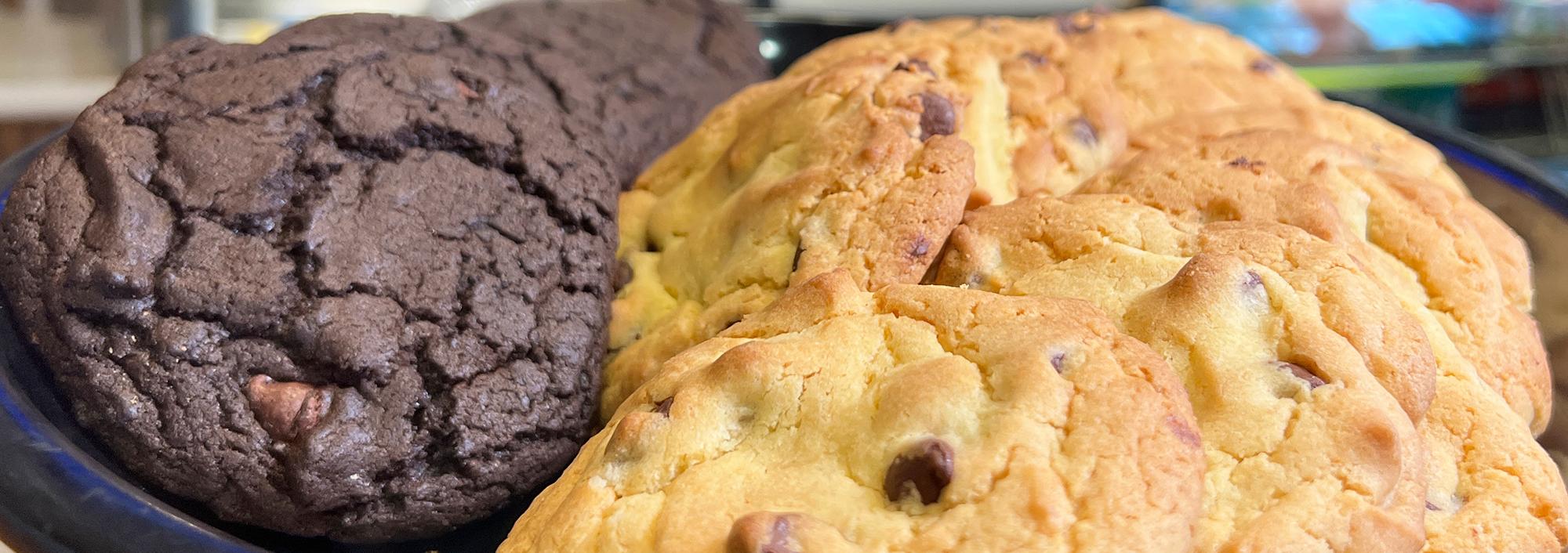 Tray that is half full with dark brown chocolate cookies and half full of chocolate chip cookies