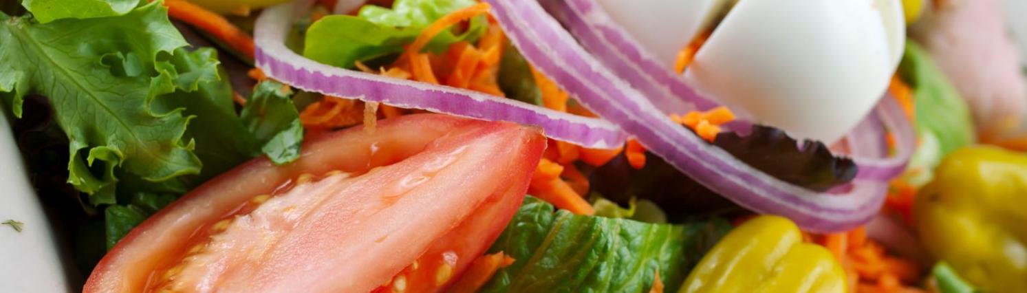 Close up of salad with lettuce, peppers, red onion, boiled egg and shredded carrot