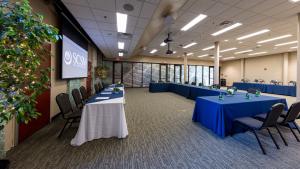 Large room with tables set up in u shape facing another line of tables and projector screen 