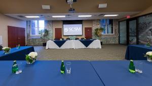 Tables with blue table cloths set up in U shape facing two tables with large screen in the Gervais St. Room.