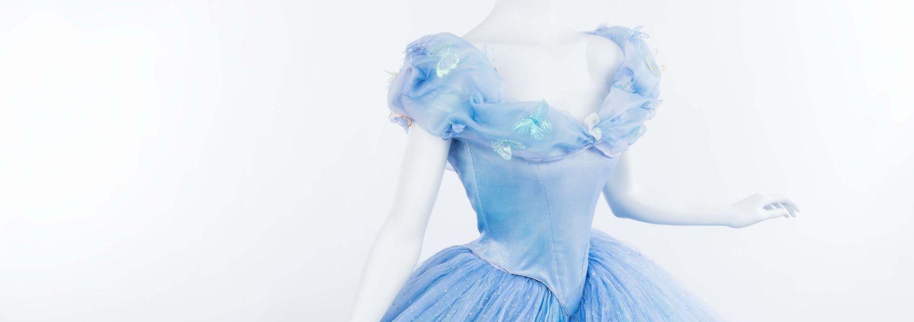 Mannequin on white background wearing light blue off the shoulder ballgown with twirling skite in light blue layers of chiffon.