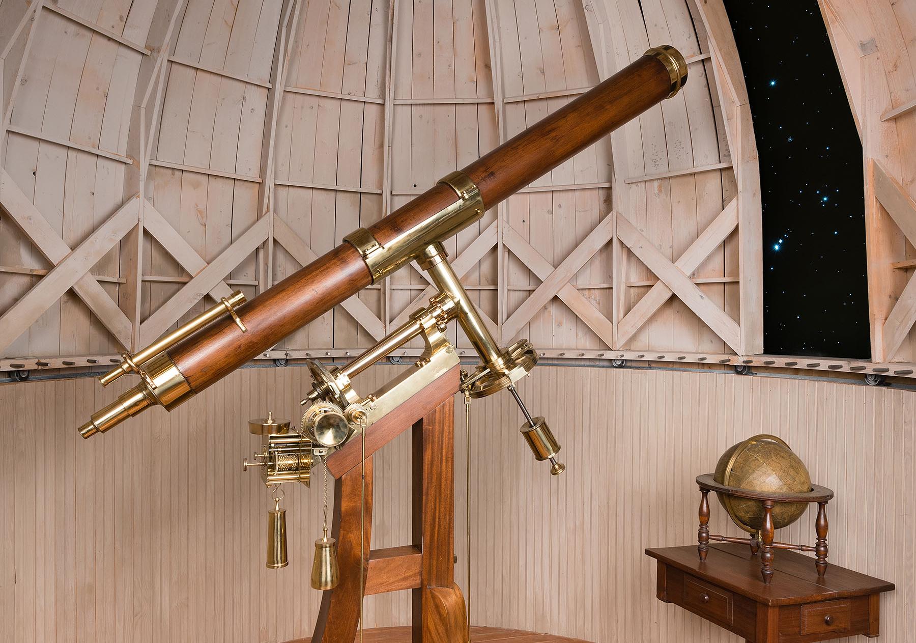 Brass and wood telescope stands on base under a fake observatory dome 