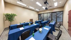 Room with tables with blue table cloths set up facing a speaker's podium