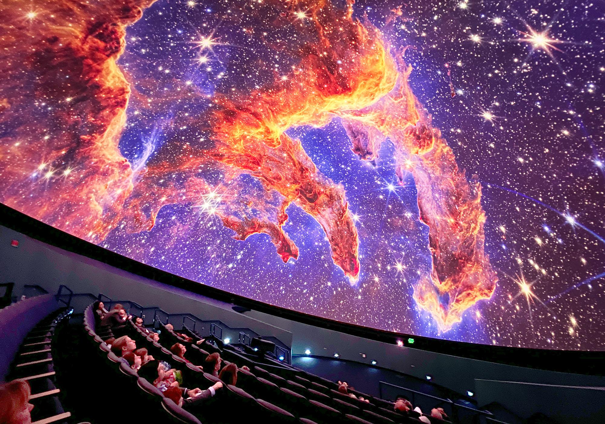 Guests in the planetarium dome look up at projection of the Pillars of Earth on the planetarium dome