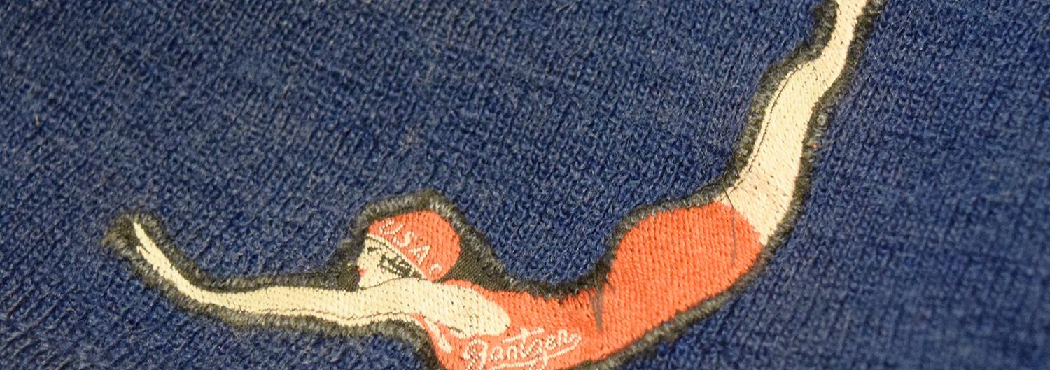 Circa 1920 Jantzen men's wool bathing suit. Blue with a signature logo on their suits, depicting a diving woman in a bright red suit.
