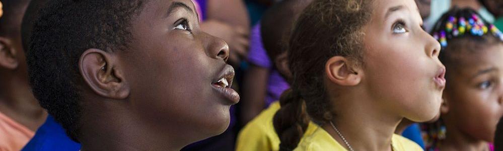 A young boy and girl look up in awe at something out of frame
