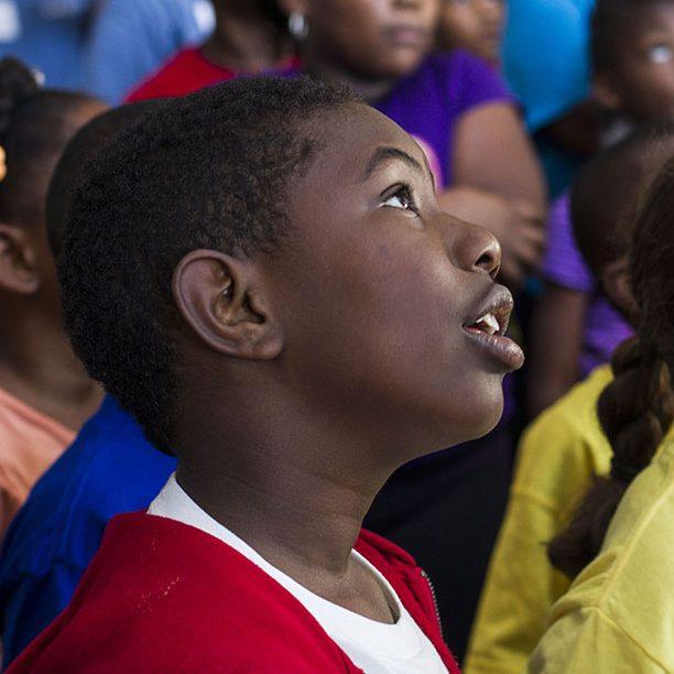 A young boy and girl look up in awe at something out of frame