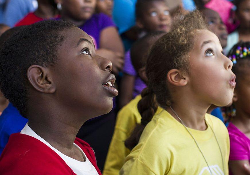 A young boy and girl look up in awe at something out of frame