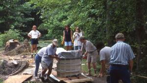 Group of people outside moving a large, wrapped object on a pallet