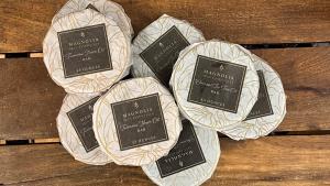 Multiple Round Bars of Soaps Wrapped in White Paper With a Brown Label Reading Magnolia Soaps