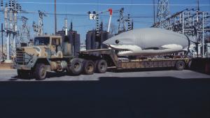 Giant Megalodon replica sits on the back on a National Guard flatbed truck in a parking area