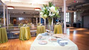 Table with white tablecloth and white dishes with Large white floral arrangement set up in an open space with wood flooring