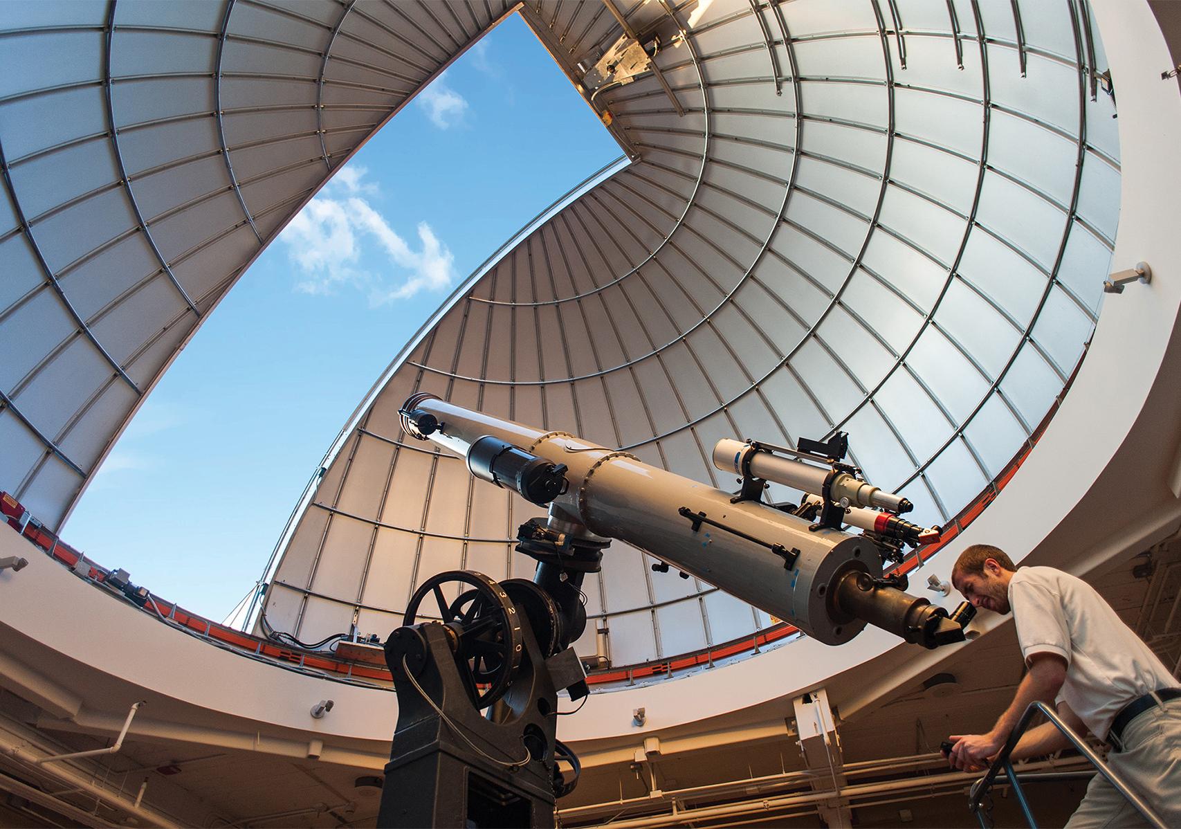 Observatory Educator Looks Through Alvan Clark Telescope During Solar Observing Hours With Dome Open Above Him Showing Blue Sky