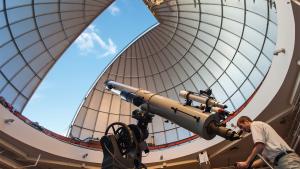 Observatory Educator Looks Through Alvan Clark Telescope During Solar Observing Hours With Dome Open Above Him Showing Blue Sky
