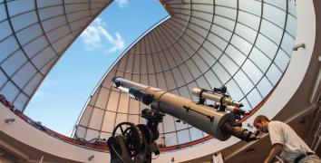 Observatory Educator Looks Through Alvan Clark Telescope During Solar Observing Hours With Dome Open Above Him Showing Blue Sky