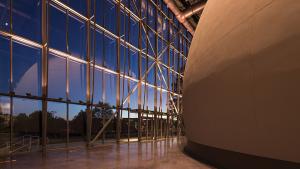 Planetarium dome exterior visible on right side with large glass wall on left showing that it is night outside