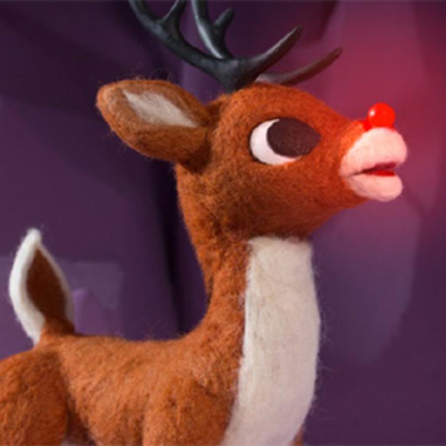 Rudolph the Red Nosed Reindeer with glowing nose stands against a purple background.