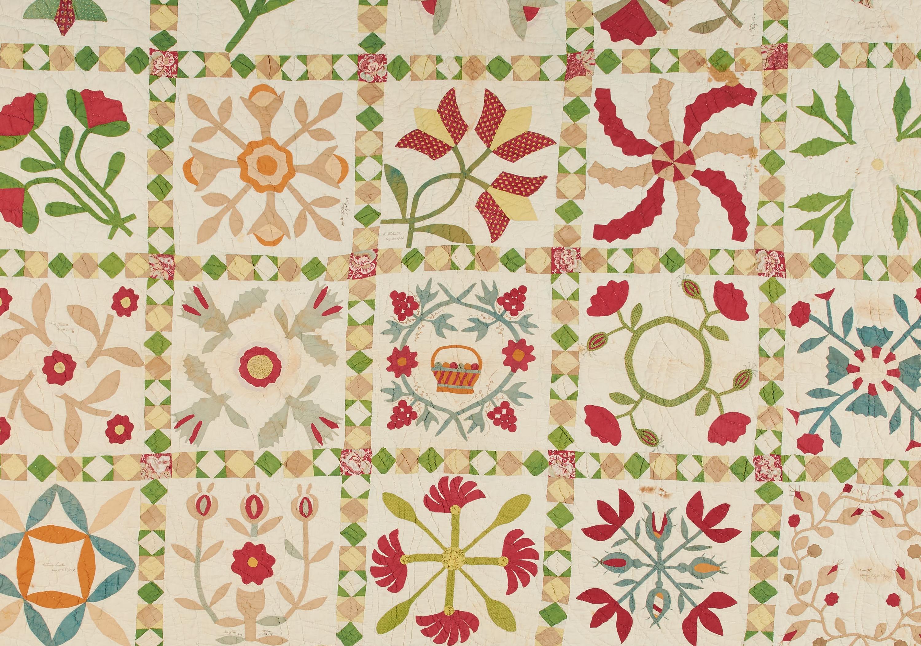 a quilt with green, red and yellow flowers on a cream colored background