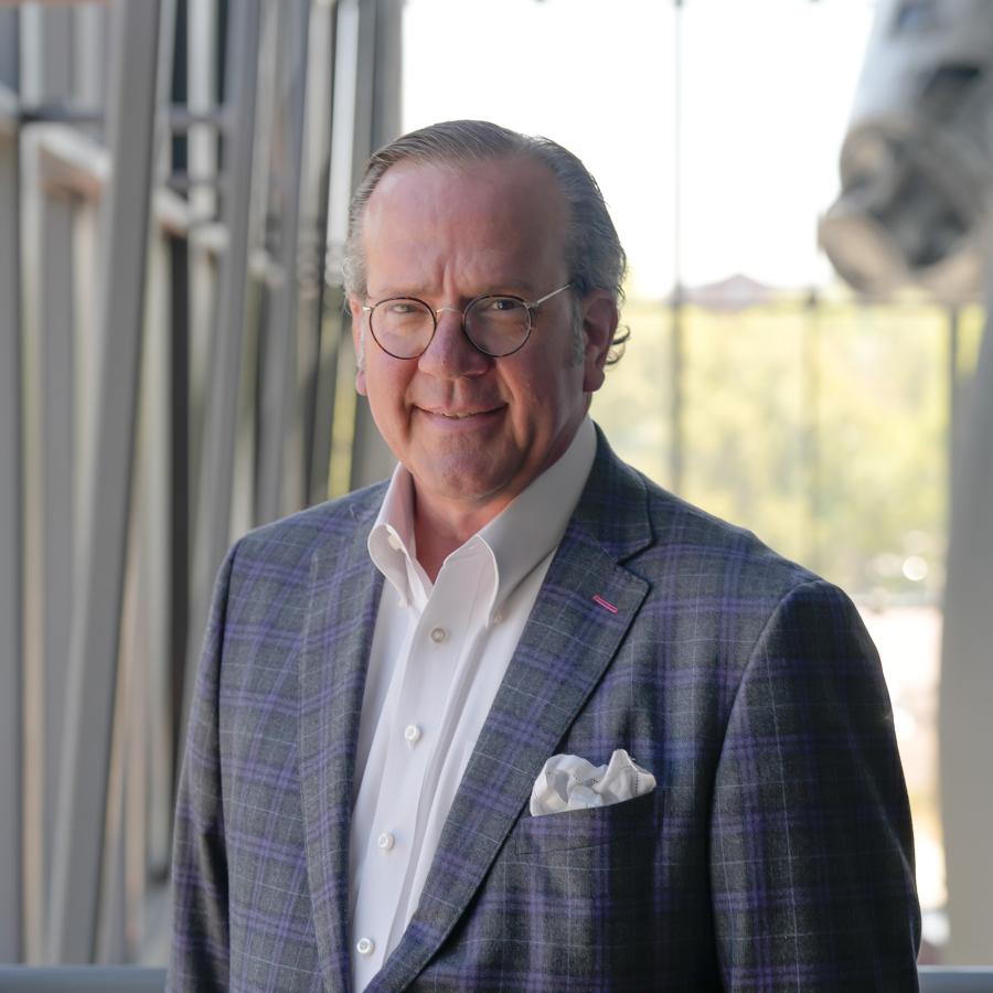 Man in grat suit jacket with white shirt smiles at camera