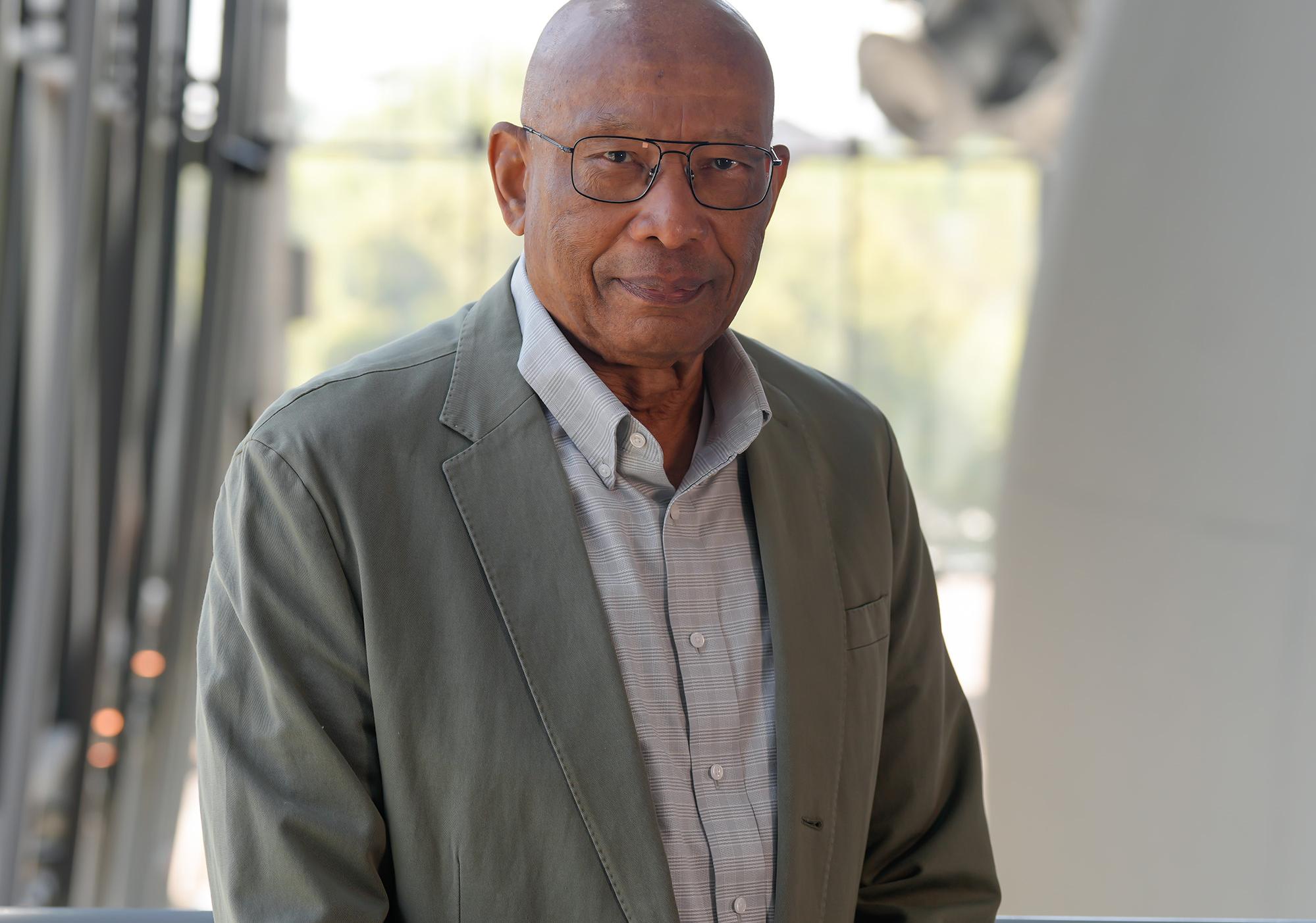 Man in gray suit jacket smiles at camera