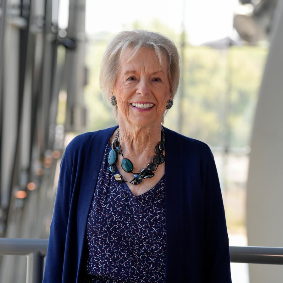 Woman with short light colored hair wearing navy blue cardigan smiles at camera