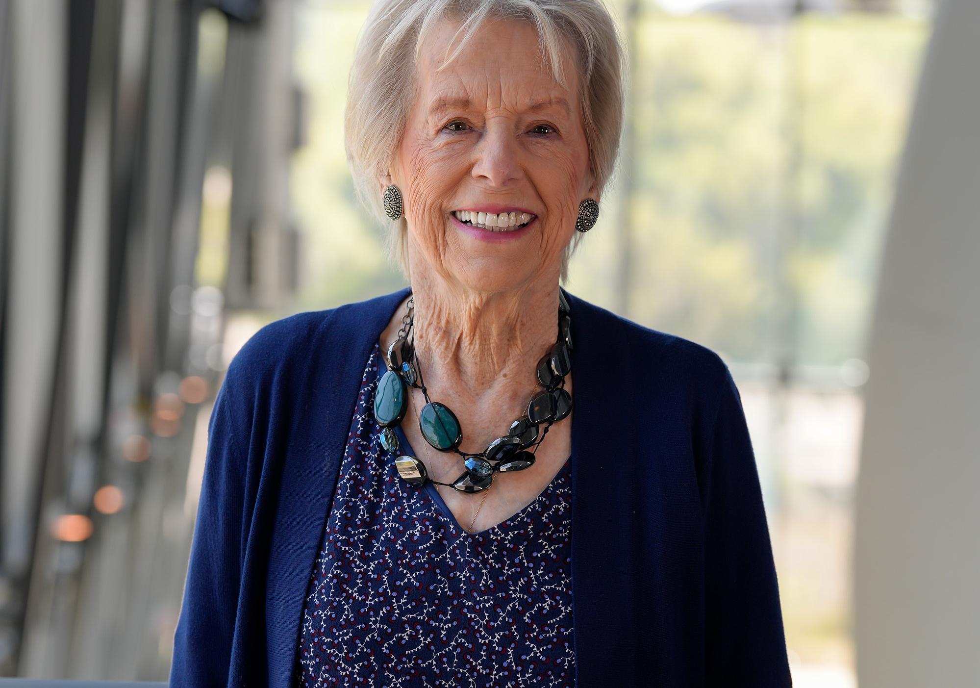 Woman with short light colored hair wearing navy blue cardigan smiles at camera