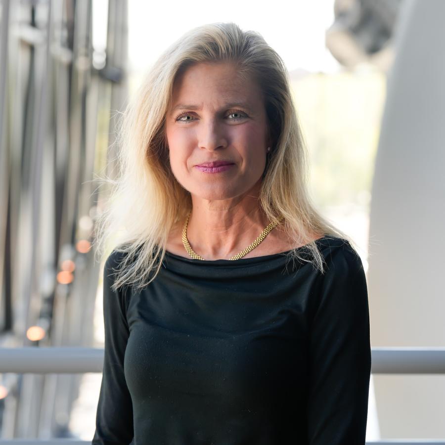 Woman with blonde hair wearing black blouse smiles at camera