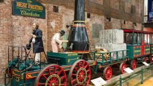 Full size train replica of The Best Friend of Charleston at the State Museum. Shows green train with red wheels and black smoke stack.