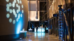 Planetarium lobby during evening reception shows the side of the large dome exterior on the left with circular lights projected on it 
