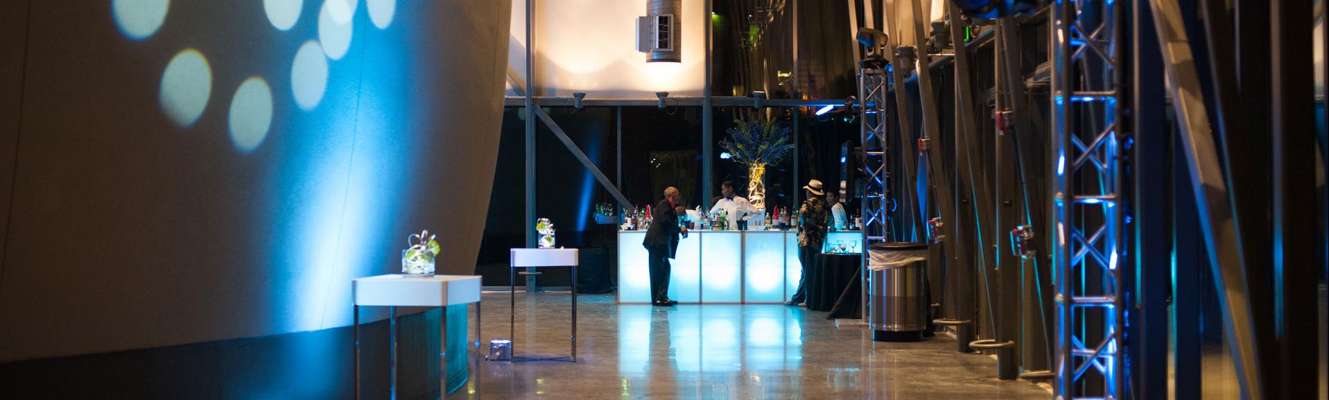 Planetarium lobby during evening reception shows the side of the large dome exterior on the left with circular lights projected on it 