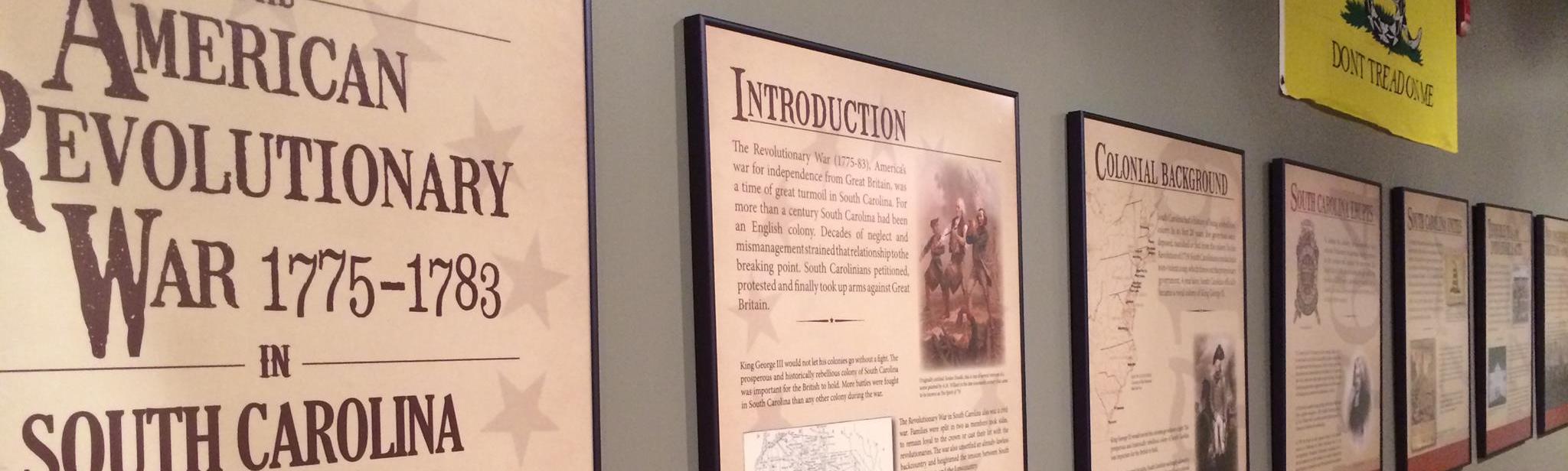 Tan wall with 7 text panels hanging on the wall about the American Revolutionary War in South Carolina