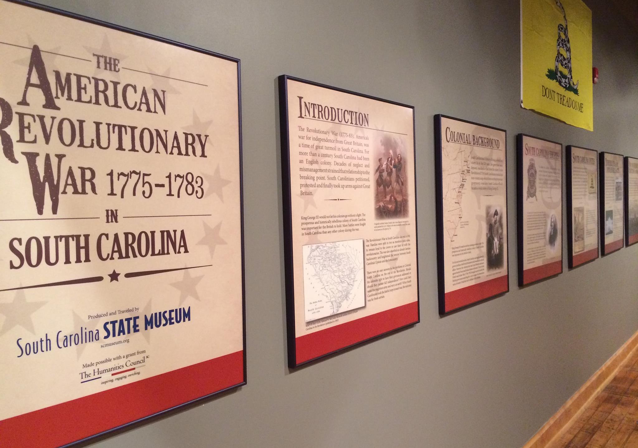 Tan wall with 7 text panels hanging on the wall about the American Revolutionary War in South Carolina