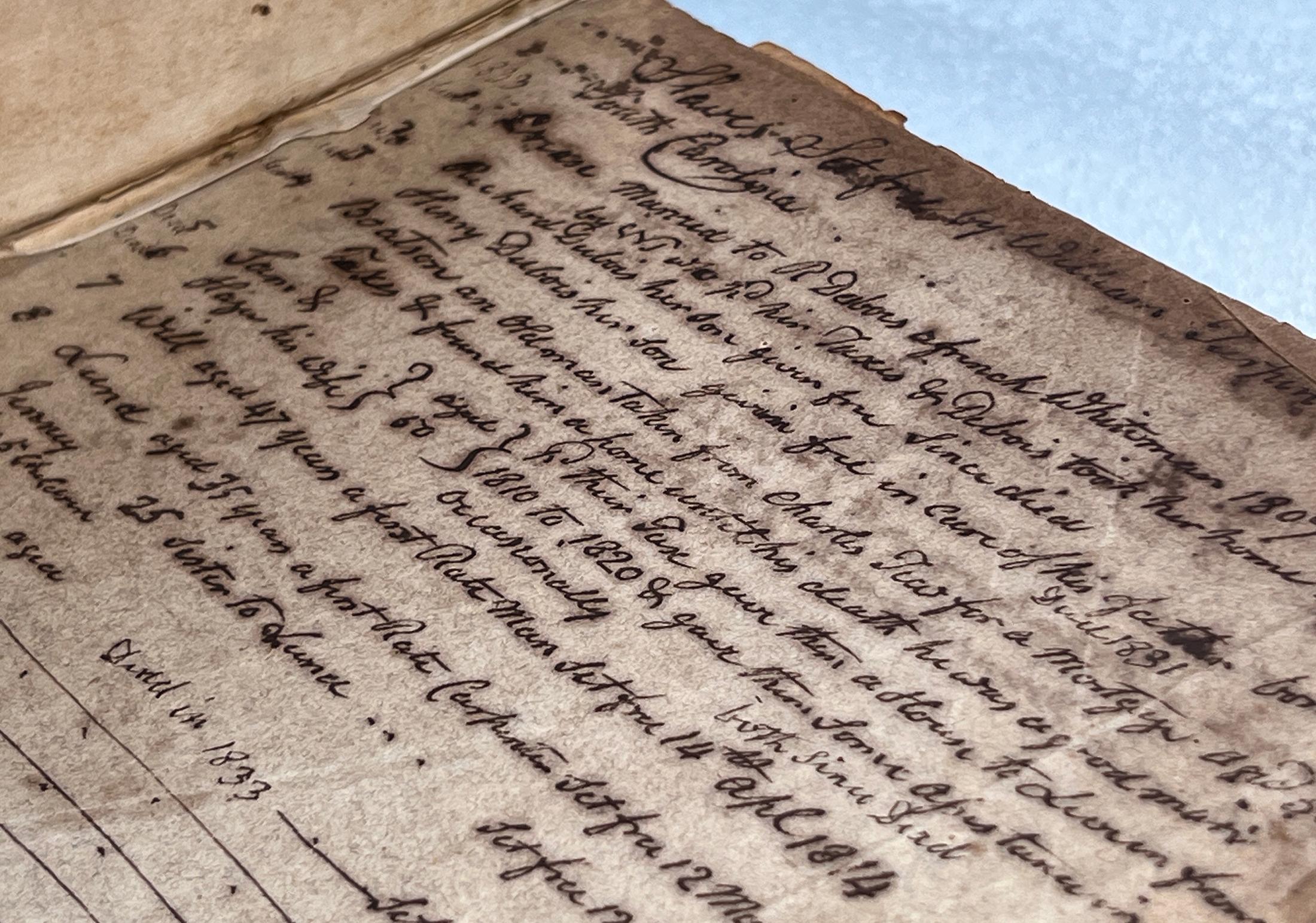 A man and woman bend down towards a table to examine a large, old leather bound book