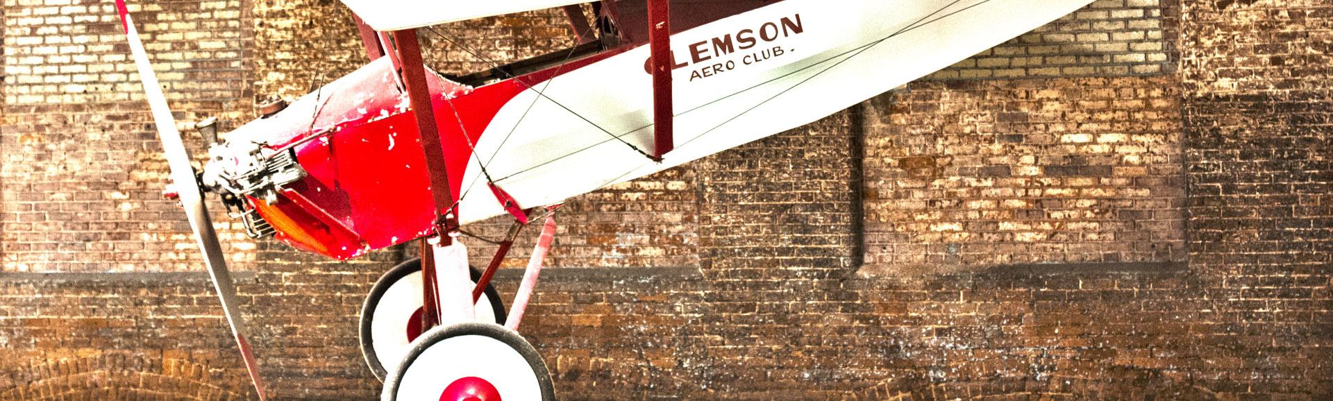Red and white propeller airplane is suspended from the ceiling on display at the South Carolina State Museum.