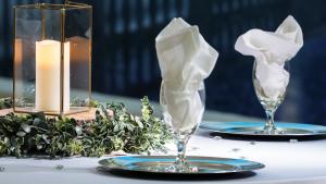 Close up of formally set table with white cloth napkins and mural showing lighted bridge in the background