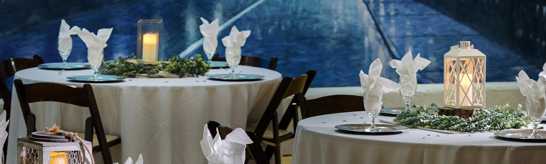 Three formally set table with the white table cloths and napkins with painted mural of bridge in the background