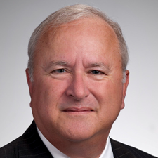 Man wearing dark suit, white shirt and red tie