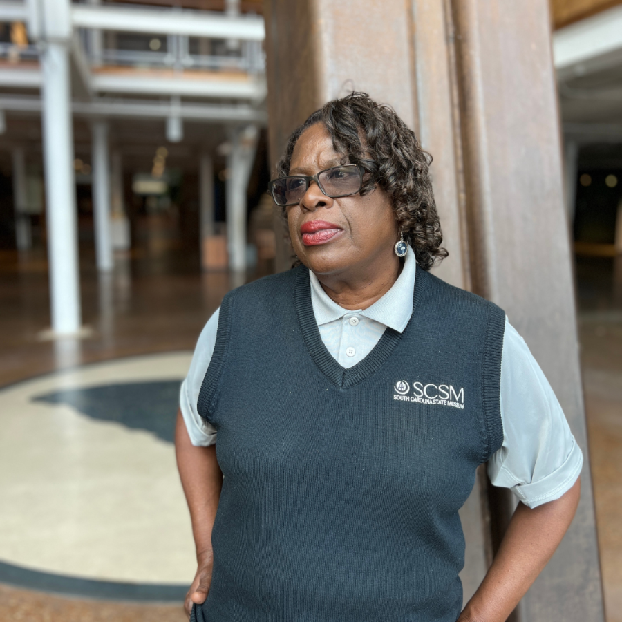 Woman in navy blue vest with museum logo poses for camera